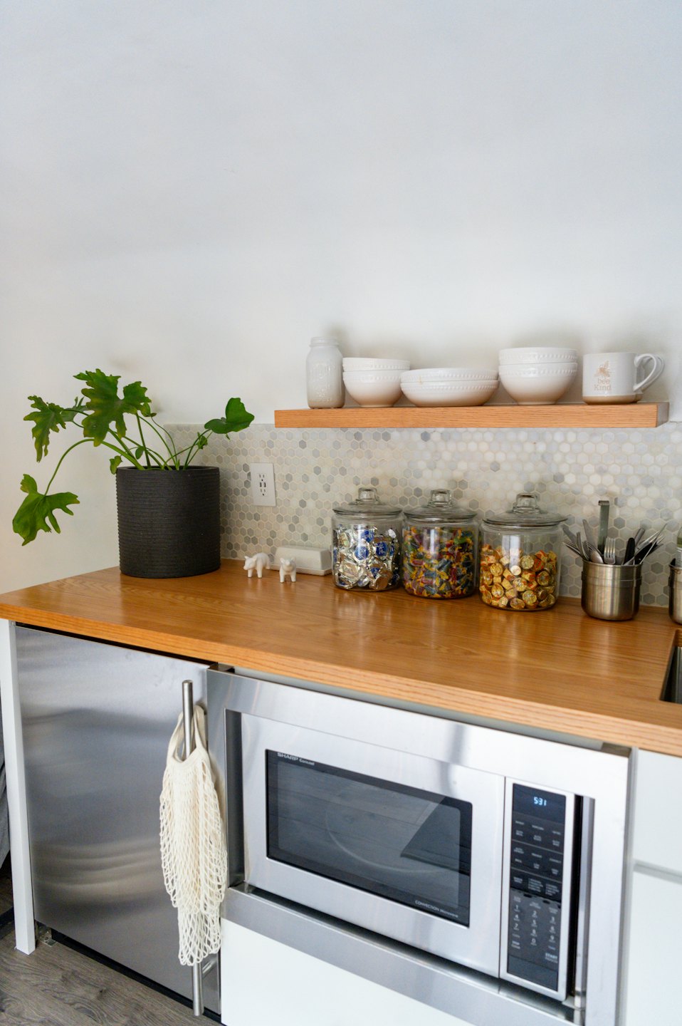 Modern kitchen counter featuring organized jars, bowls, and greenery.